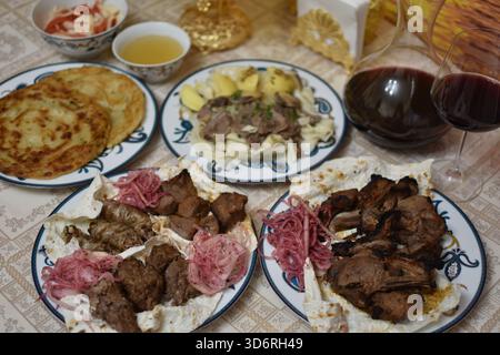 Gegrilltes Fleisch, einschließlich Lamm, Huhn und Lyulya-Kebab, Beshbarmak und Rotwein in Glaskaraffe Stockfoto