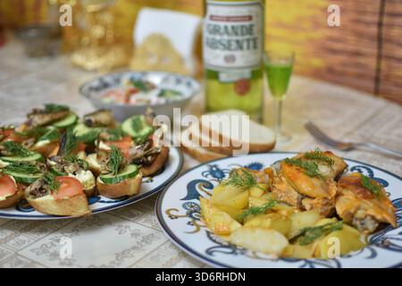 Grand Absente Absinth mit gebratenem Huhn, Kartoffeln und Sandwiches mit Fisch und Gemüse Stockfoto
