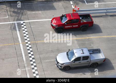 Roter Pick-Truck des Sicherheitsteams und offizielles silbernes Fahrzeug auf der Ziellinie der Rennstrecke. Luftaufnahme des leeren Asphaltkreises zeigt den professionellen Eindruck Stockfoto