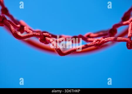 Ein rotes Basketballnetz, das vor einem klaren Himmel umrissen ist. Stockfoto