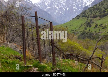 Rostiger Maschendrahtzaun mit rotierendem Wickel in den Bergen Kirgisistans Stockfoto