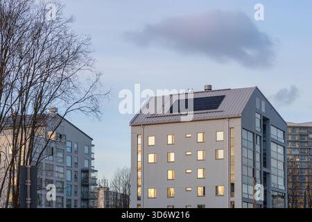 Solarpaneele, die auf den Dächern von Wohnhäusern installiert sind und an einem sonnigen Tag erneuerbare Energie in einem vorstädtischen Stadtteil erzeugen Stockfoto