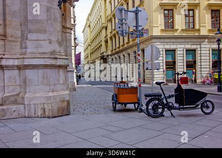 Ruhige, enge Straße in Wien, gesäumt von historischen gelben Gebäuden, die zwei Lastenräder zeigen Stockfoto