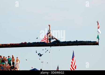 Ein junger Mann rutscht auf dem fetten Stab, während er versucht, die Flagge während des St. Peter’s fest in Gloucester, Massachusetts, zu ergreifen Stockfoto