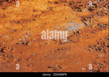 Nahaufnahme der verwitterten Roststruktur mit abblätternden Schichten und warmer orangefarbener Patina, detaillierter Hintergrund der industriellen Oberfläche. Stockfoto