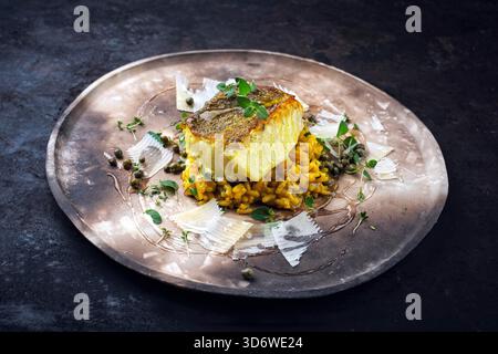 Gebratenes Fischfilet aus nordischem Kabeljau mit safran-Risottoreis, grünem Gemüse und Parmesankäse Stockfoto