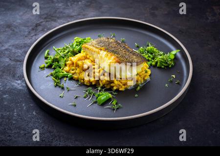 Gebratenes Fischfilet aus nordischem Kabeljau mit safran-Risottoreis, grünem Gemüse Stockfoto