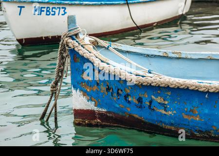 Marsaxlokk, Malta - 13. April 2025: Traditionelle, farbenfrohe maltesische Fischerboote namens Luzzu mit hellblauen, gelben und roten Details, die im malerischen Hafen von Marsaxlokk ankern Stockfoto