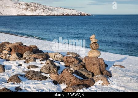 Winter auf der Barentssee. Ein Steinhaufen am Strand in Teriberka, Region Murmansk Stockfoto