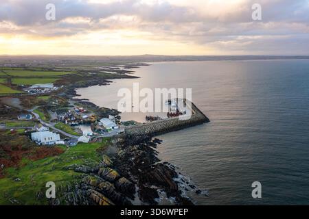 Blick aus der Vogelperspektive auf Port Oriel in Clogherhead mit Fischerbooten und trübem Abendlicht entlang der ruhigen Küste Stockfoto