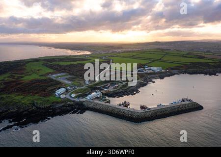 Blick aus der Vogelperspektive auf Port Oriel in Clogherhead mit Fischerbooten und trübem Abendlicht entlang der ruhigen Küste Stockfoto
