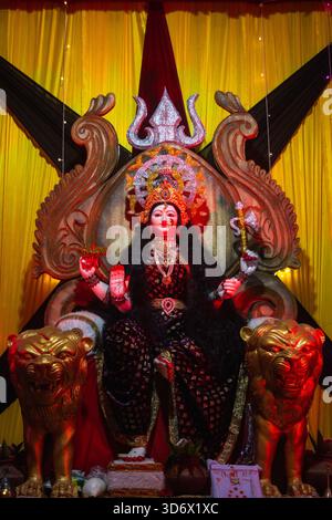 Sitzender hindugottes Idol auf Thron, flankiert von goldenen Löwen Stockfoto