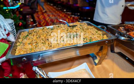 Buffettablett gefüllt mit gewürztem Reis gemischt mit Gemüse und Kräutern, serviert in einem warmen Ambiente während einer Veranstaltung mit Catering. Stockfoto