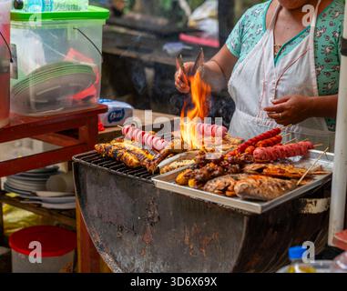 Straßenverkäufer grillen Fisch, Huhn und Spieße über offener Flamme im peruanischen Amazonas und zeigen traditionelle Outdoor-Küche und lokale Esskultur. Stockfoto
