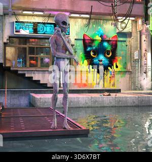 3D-Illustration von zwei grauen Außerirdischen mit einem Außerirdischen, der in einer verlassenen Gasse steht, mit Graffiti im Hintergrund. Stockfoto