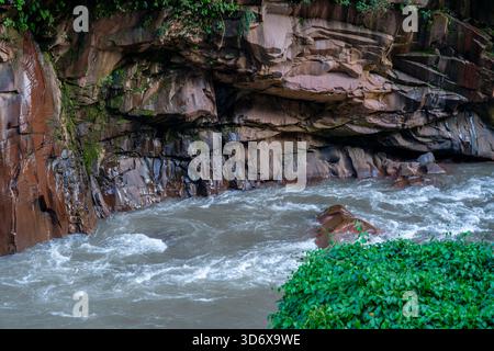 Der Fluss fließt neben geschichteten Felswänden in Tingo María, Peru, mit Erosion, natürlichen Mustern und Amazonaslandschaft. Stockfoto