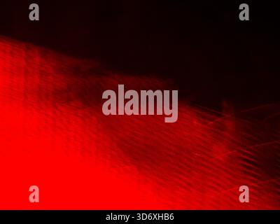 Rote Lichtstreifen überqueren einen dunklen Hintergrund und schaffen eine abstrakte, dynamische Textur und einen fließenden Energiedidienten, der für verschiedene moderne Designs geeignet ist Stockfoto