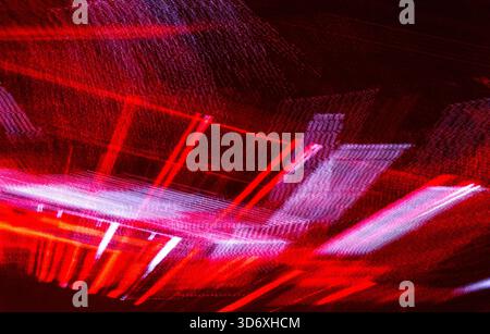 Abstrakte Lichtspuren schaffen einen dynamischen und chaotischen Hintergrund, der rote, rosa und violette Farben mit Elementen der Bewegungsunschärfe kombiniert und veloci repräsentiert Stockfoto