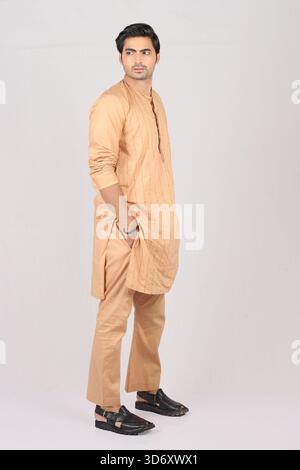 Porträt eines jungen pakistanischen Mannes im traditionellen Kurta-Pyjama im Stil vor weißem Hintergrund Stockfoto