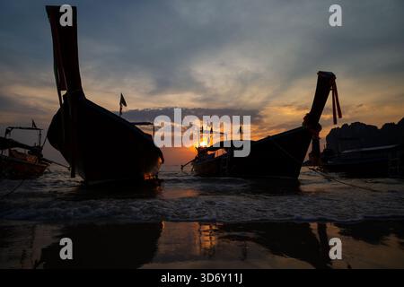 Wunderschöner Blick auf die Silhouette von Langboot-Booten am Strand, Meer und atemberaubenden Himmel bei Sonnenuntergang am Railay West Beach in Railay, Krabi, Thailand. Stockfoto