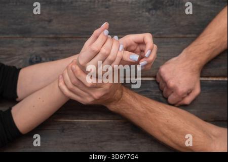 Weibliches Handgelenk, das von einer starken männlichen Hand gehalten wird, symbolisiert Fragilität, Machtungleichgewicht, Schutzbedürftigkeit, Verletzlichkeit zeigen Emotionen. Weibliche Verletzlichkeit A Stockfoto