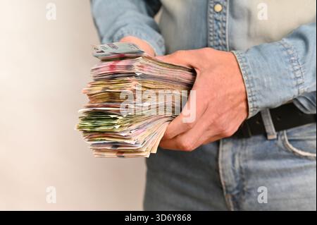 Nahaufnahme der Hände mit großen Banknotenstapeln, Konzept des finanziellen Gewinns und des wirtschaftlichen Wohlstands. Die Person stellt einen dicken Kassenstapel vor, der W repräsentiert Stockfoto