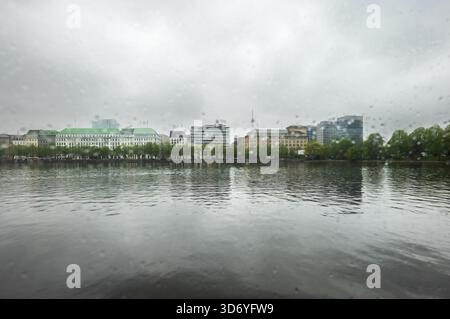 Regnerischer Novembertag in Hamburg, durch ein mit Regentropfen bedecktes Fenster mit verschwommenem, grauem Blick auf die Stadt. Stockfoto