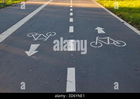 Markierungen auf einem Radweg-Führer in Neuss. Die Sonne scheint auf dieser gut gepflegten Route, die das Radfahren in der Stadt fördert. Stockfoto