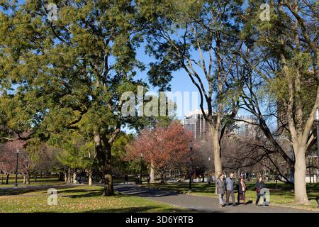 Gruppe von Senioren, die am sonnigen Herbsttag im Boston Common unter Bäumen spazieren gehen Stockfoto