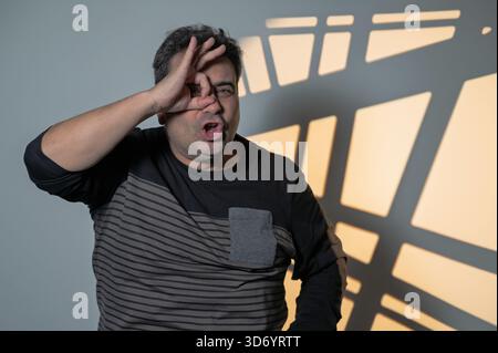 Ein reifer Mann macht eine lustige OK-Geste mit der Hand über einem Auge Stockfoto
