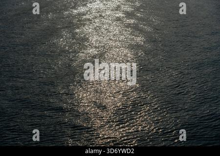 Wunderschöne Sonnenuntergangsreflexion funkelt auf winzigen Wellen der Meereswasserwelle im Hintergrund, Draufsicht. Die Textur des Meerwassers. Stockfoto