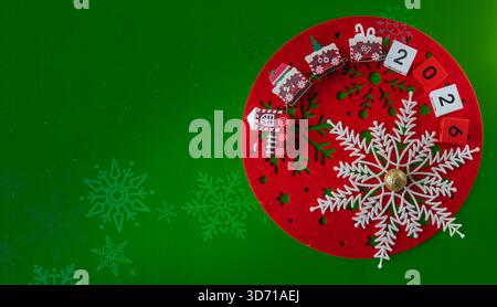 Weihnachtsdekor in roter Schneeflocke mit festlichen Blöcken, die die Feiertagsnummer 2026 auf grünem Hintergrund zeigen Stockfoto