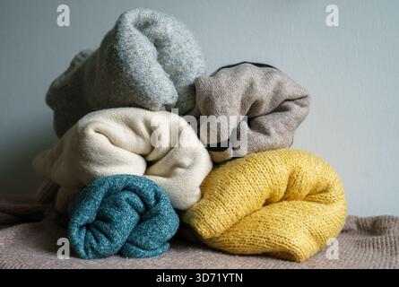 Verschiedene gestrickte und gefaltete Pullover aus Wolle und Kaschmir in Pastellfarben liegen übereinander. Stockfoto