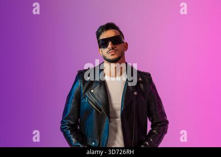 Coole Serious Young Arab man in Sonnenbrille posiert selbstbewusst in stilvoller Lederjacke Stockfoto