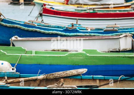 Marsaxlokk, Malta - 13. April 2025: Traditionelle, farbenfrohe maltesische Fischerboote namens Luzzu mit hellblauen, gelben und roten Details, die im malerischen Hafen von Marsaxlokk ankern Stockfoto