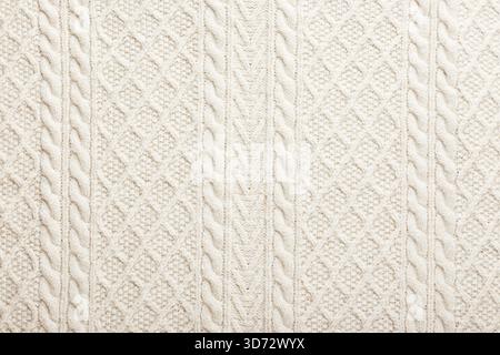 Pullover oder Schal mit großer Strickstruktur. Gestrickter Jersey-Hintergrund mit Reliefmuster. Zöpfe beim Stricken. Handgestricktes Wollmuster oder maschinelles Strickmuster. Stoffhintergrund. Stockfoto
