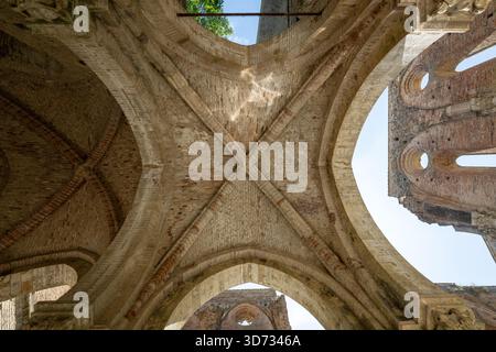 Rippengewölbe und gotische Bögen der Ruine der Zisterzienserabbazia di San Galgano aus dem 13. Jahrhundert in Chiusdino, Toskana. Stockfoto