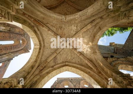 Blick nach oben auf gotische Rippengewölbe und Ziegelbögen in der Ruine der Zisterzienserabtei San Galgano in der Nähe von Chiusdino, Toskana. Stockfoto