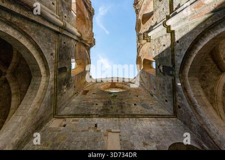 Blick nach oben in die gotische Abbazia di San Galgano ohne Dach in der Nähe von Chiusdino mit Steingewölben, Bögen und verwitterten Mauerwerken. Stockfoto