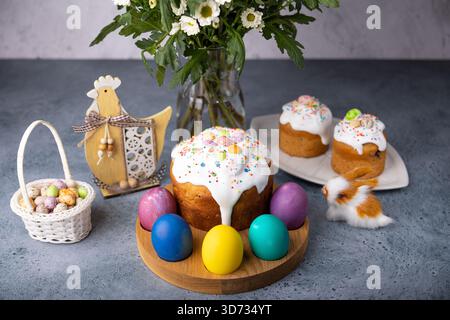 Osterkulich mit kandierten Früchten in weißer Glasur mit bunten Streuseln und bemalten Eiern. Traditionelles Ostergebäck. Osterferien. Nahaufnahme, wählen Sie Stockfoto