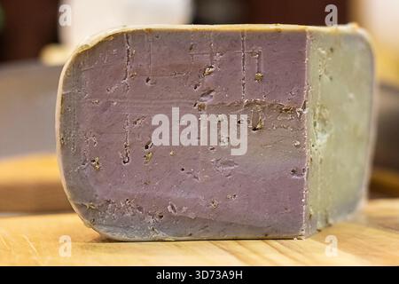 Violetter Käseblock auf Holzbrett, rustikale Käseverkostung für Gourmetküche Stockfoto