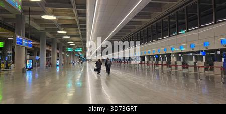 Doloman, Türkei - 25. April 2025: Gäste des modernen Flughafenterminals gehen zu den Check-in-Schaltern mit heller Beleuchtung. Stockfoto