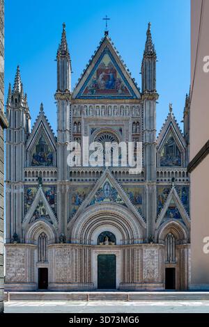 Die Kathedrale von Orvieto, ein gotisches Meisterwerk in Italien, verfügt über eine atemberaubende polychrome Fassade mit komplexen Mosaiken und Skulpturen. Von der sonnendurchfluteten Fassade eingerahmt Stockfoto