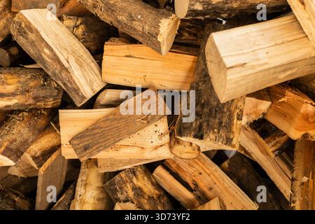 Ein Stapel von Brennholzstämmen ist übersichtlich angeordnet und zeigt verschiedene Holzarten und -Texturen. Diese Kollektion ist ideal für Wärme bei Kälte Stockfoto