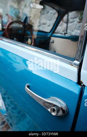 Nahaufnahme eines verchromten Türgriffs eines blauen Oldtimers. Stockfoto