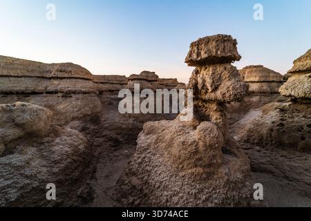 Salzpilzartige Formationen am Toten Meer bei Sonnenaufgang, warmes goldenes Licht, das weiße Mineralkappen über ruhigem türkisfarbenem Wasser beleuchtet. Stockfoto