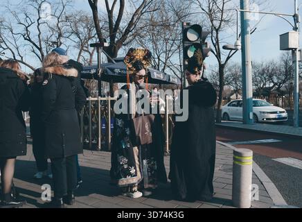 Hanfu-Königinnen warten im Winter Peking an einem grünen Licht, tragen kunstvolle Kronen und bestickte Umhänge Stockfoto