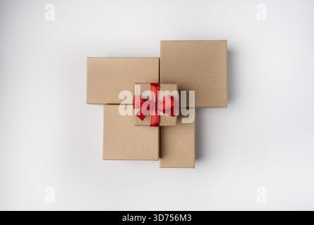 Eine mit einem roten Band gefesselte Pappschachtel liegt auf Bastelkisten auf weißem Hintergrund Stockfoto