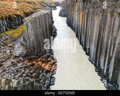 Ein atemberaubender Blick über die Drohne auf den Stuðlagil Canyon in Island, der seine majestätischen Basaltsäulen und den Milchfluss einfängt, der durch diesen fließt Stockfoto
