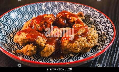 Knuspriges koreanisches gebratenes Hähnchen glasiert mit roter süßer Chili-Sauce. Klebrig, würzig-süß und perfekt gekocht. Ideal für Vorspeisen oder Hauptgerichte. Stockfoto